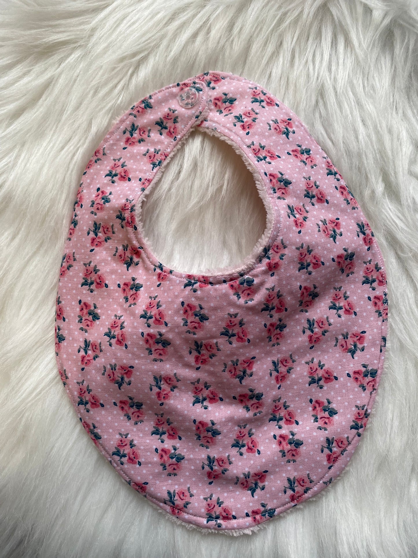 Bavoir rose avec des fleurs et des pois