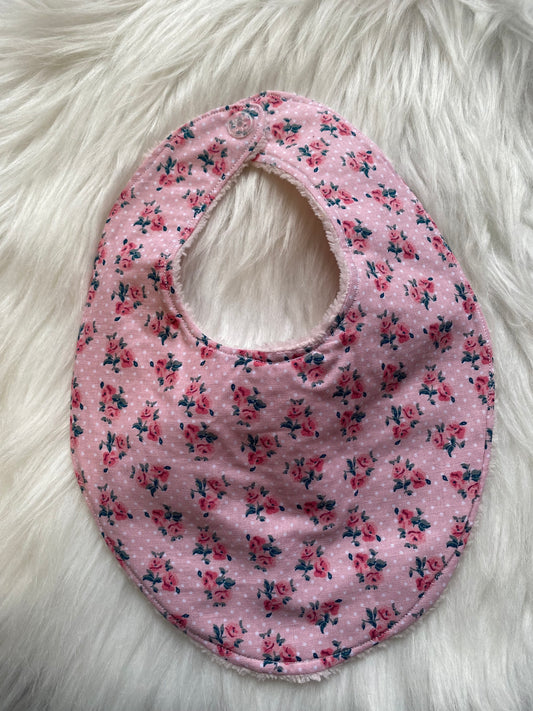 Bavoir rose avec des fleurs et des pois